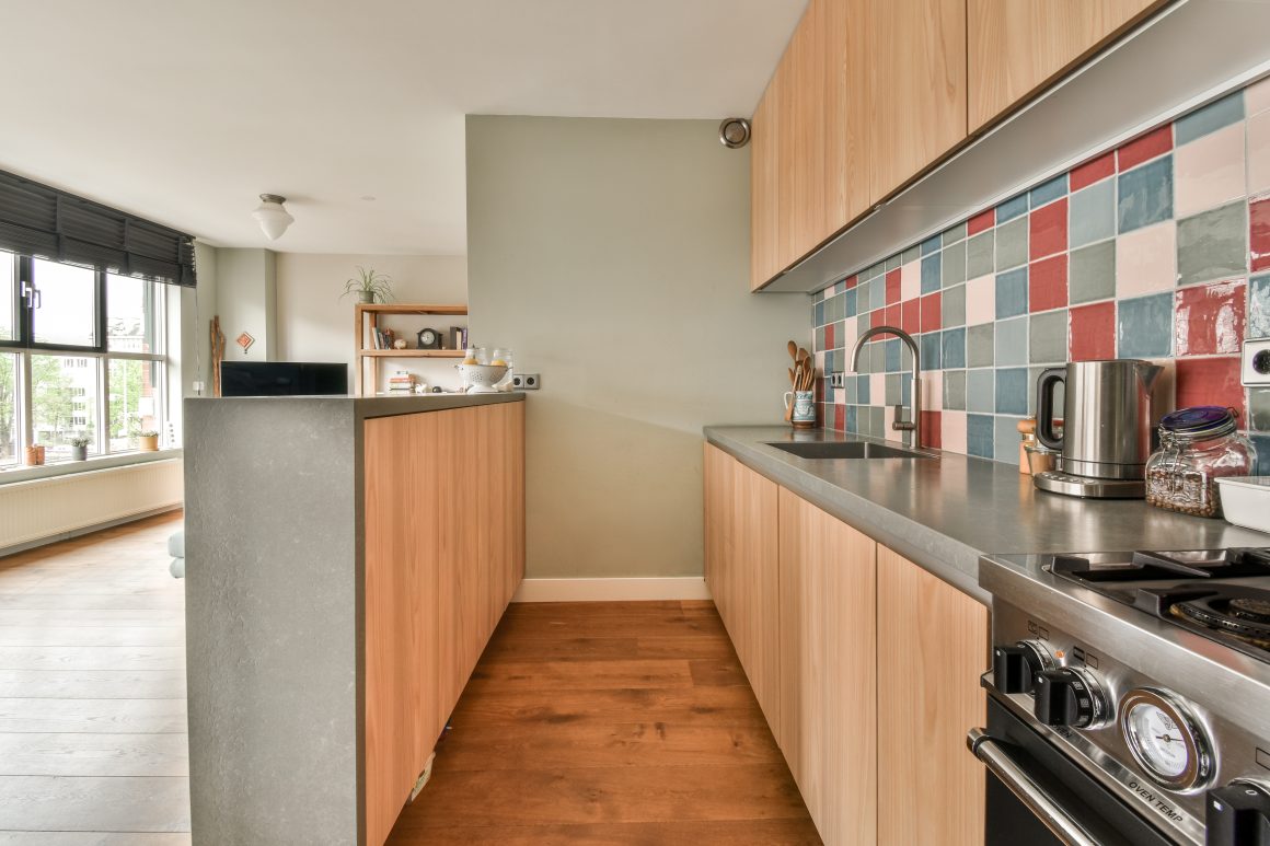 Petite cuisine avec plan de travail en béton, armoires en bois clair, espace réduit optimisé, électroménagers intégrés et éclairage naturel.