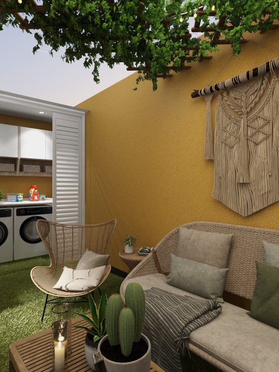 Petite terrasse aménagée avec canapé, fauteuil, plantes variées, tapis gazon et déco murale macramé.