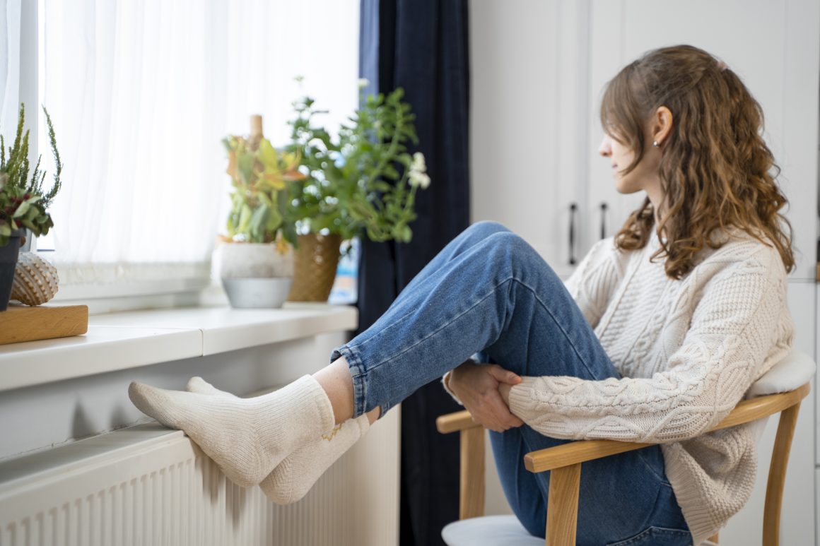 Femme assise sur chaise, regardant par la fenêtre, plantes décoratives sur rebord.