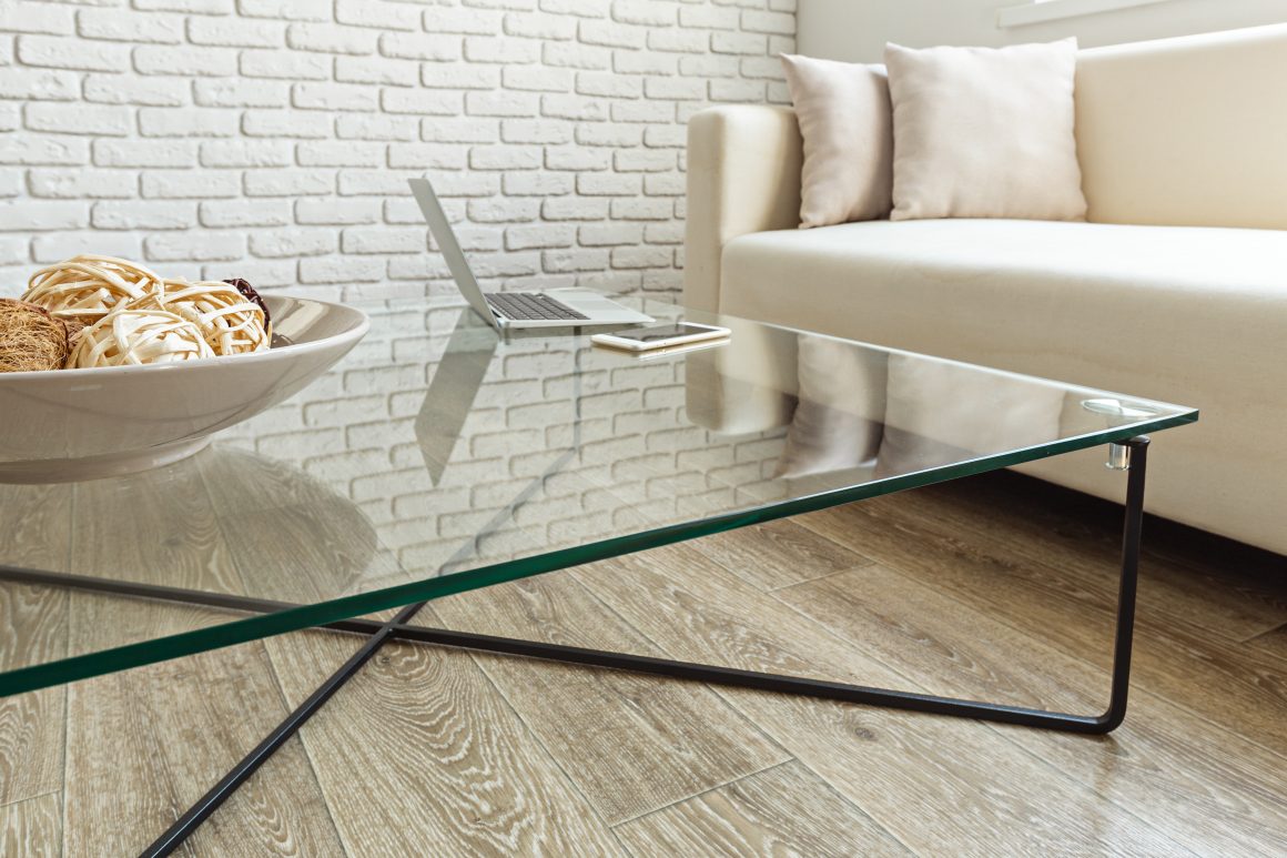 Salon minimaliste incluant un canapé beige et une table en verre