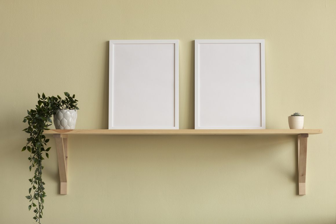 Étagère murale en bois avec plantes et cadres photo blancs vides.