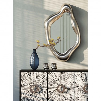 Commode décorative avec un vase bleu élégant et un miroir ondulé doré.