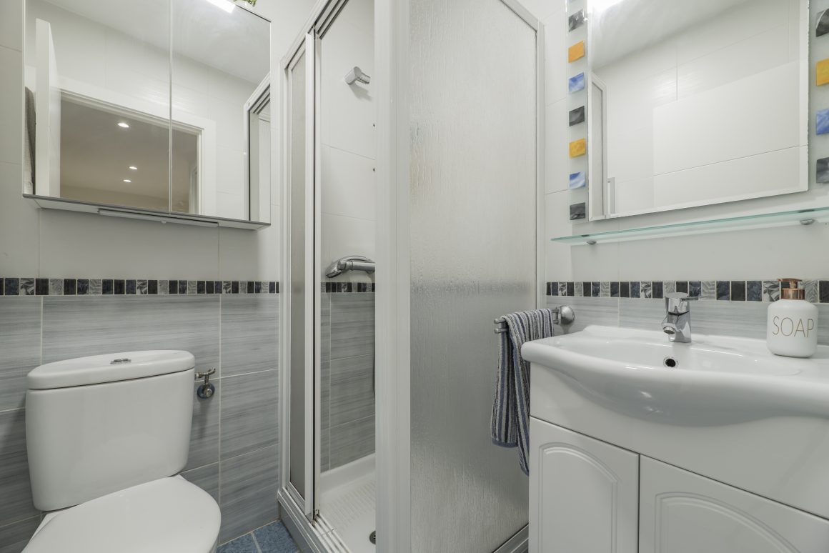 Salle de bain 4m2 aménagée avec douche cabine, carrelage gris et lavabo avec miroir et WC