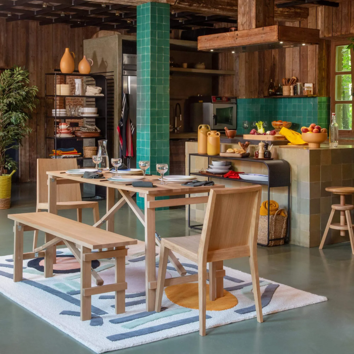 Cuisine ouverte sur salle à manger avec table pliante, chaises, tapis géométrique et accessoires décoratifs
