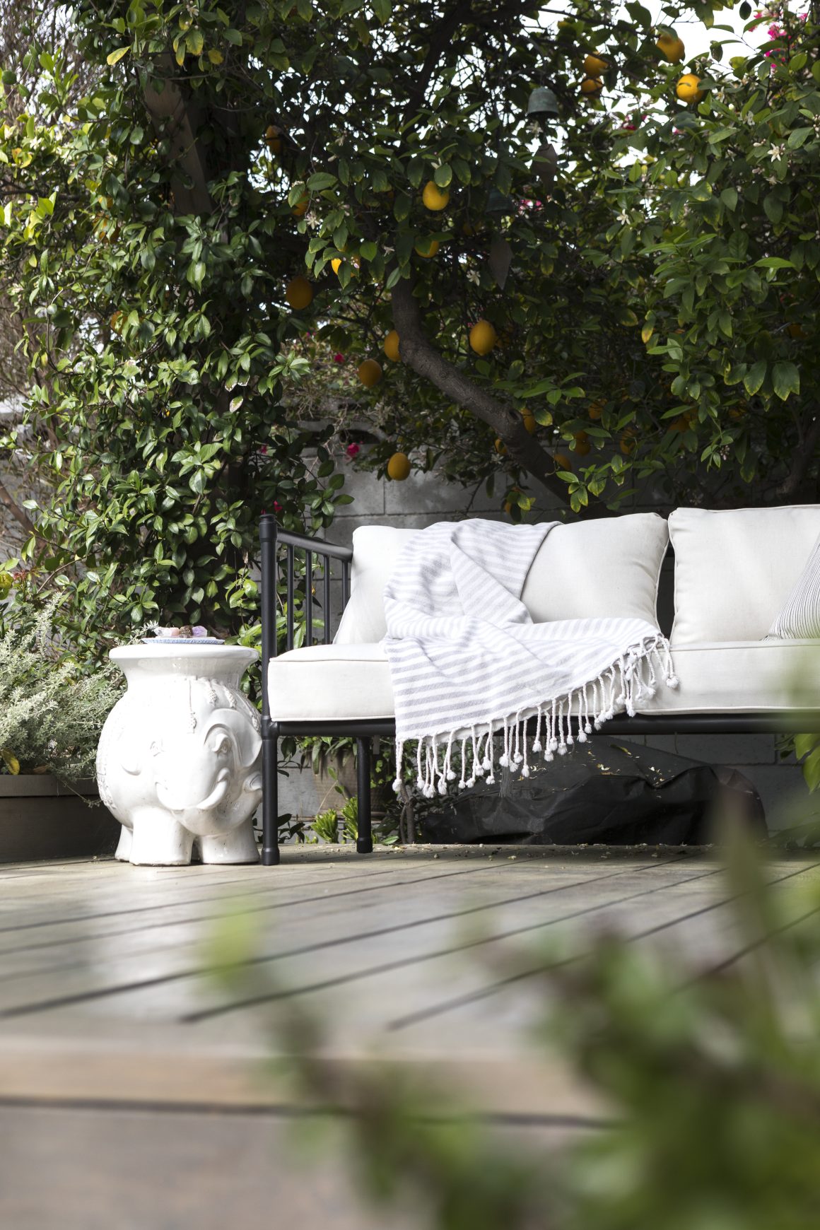 Aménagement coin jardin chaleureux avec canapé blanc et pot.