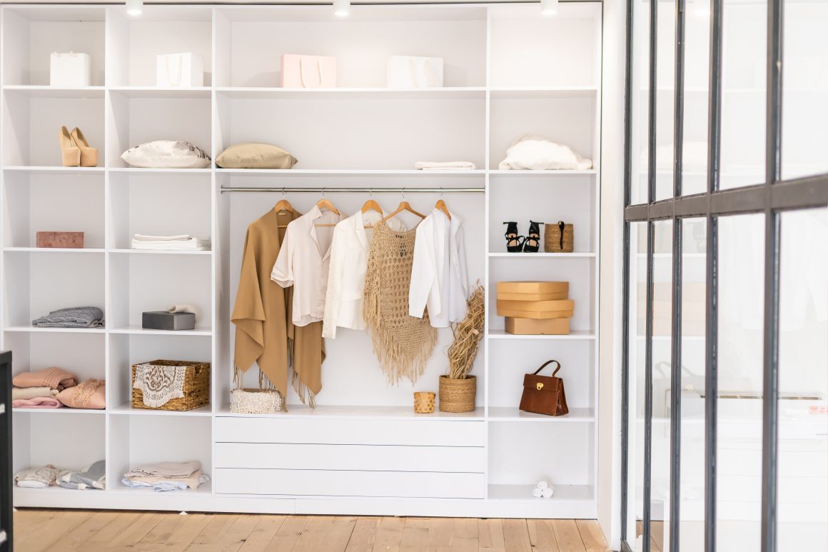 Dressing blanche avec des étagères ouvertes incluant vêtements et boîtes de rangement