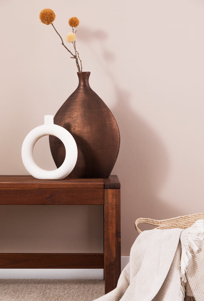 des couleurs tendance 2026 avec un meuble en bois foncé, un mur et un plaid nude devant