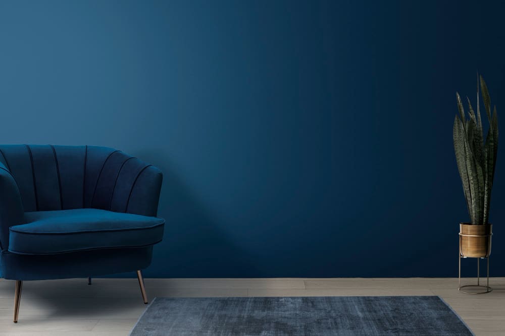 couleurs tendance 2026 dans le salon, avec le mur, le fauteuil et le tapis bleu marine