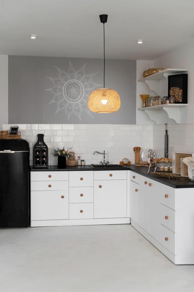 une cuisine en U dans les tons blanc et gris, avec une lampe suspendue en osier