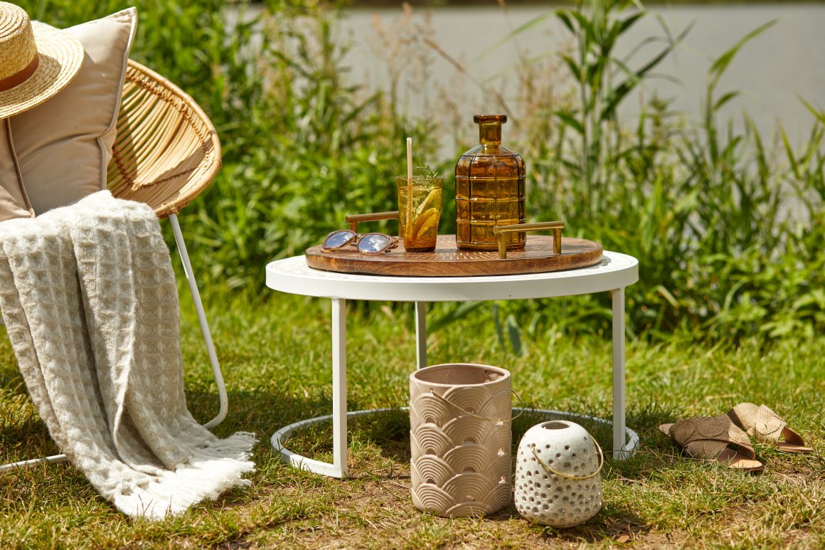 Aménagement coin salon de jardin avec fauteuil en rotin et une table basse avec des objets décoratifs