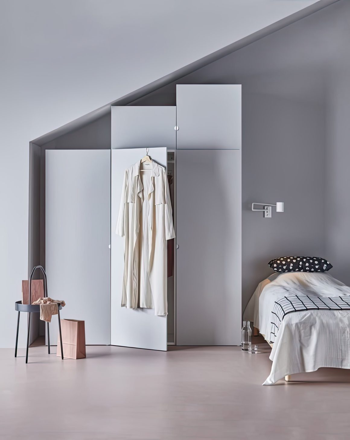 Chambre minimaliste avec lit simple, armoire sous pente, robe blanche suspendue et table basse noire
