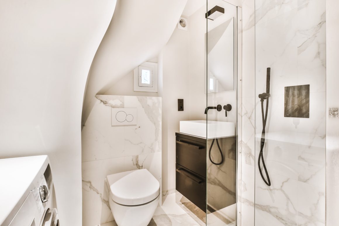 Petite salle de bain avec WC incluant meuble lave mains, douche et éclairage doux