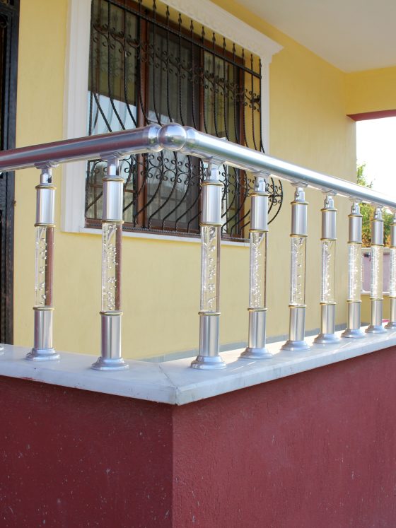 Balustrade extérieure en inox autour d'une terrasse avec murs jaune et rouge