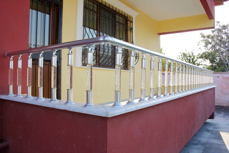 Balustrade extérieure en inox autour d'une terrasse avec murs jaune et rouge