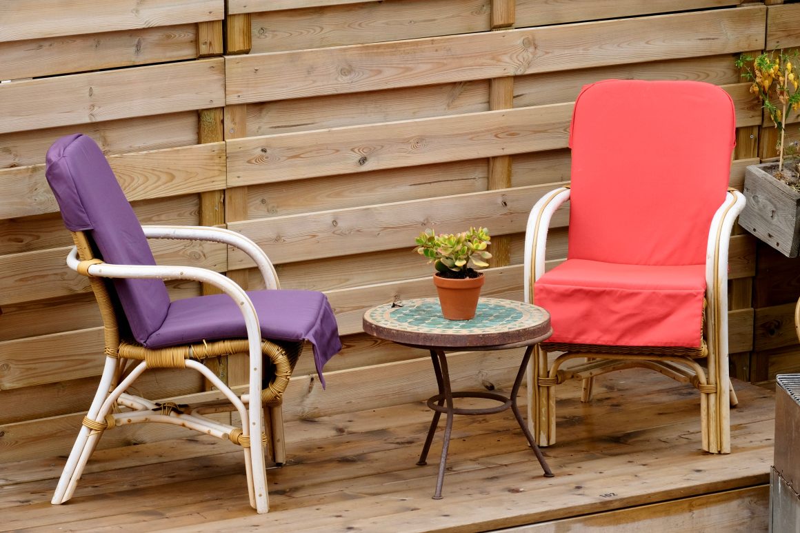 Coin jardin incluant deux chaises colorées et une petite table ronde portant une plante en pot.