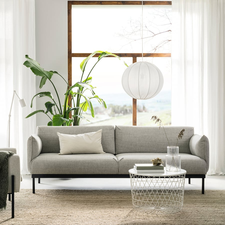 Intérieur zen avec canapé gris, table, plante, grande fenêtre bois et suspension ronde blanche.