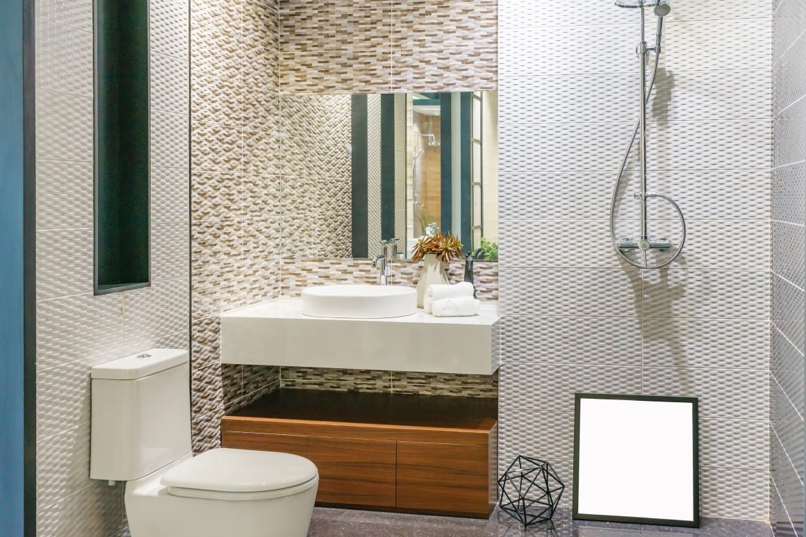Salle de bain moderne avec toilettes, douche, lavabo rond, miroir large et meuble en bois.