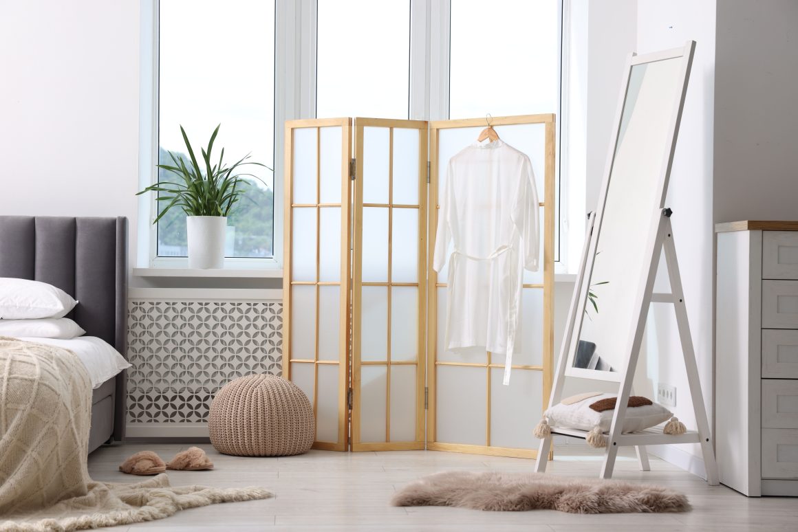 Feng shui dans une chambre avec paravent en bois, miroir, fauteuil moelleux, plante et lit cosy