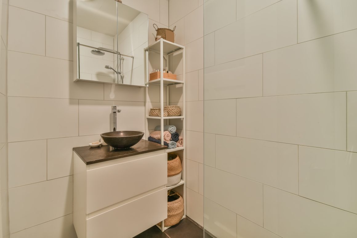 Petite salle de bain avec lavabo, miroir, rangement échelle et paniers en osier.