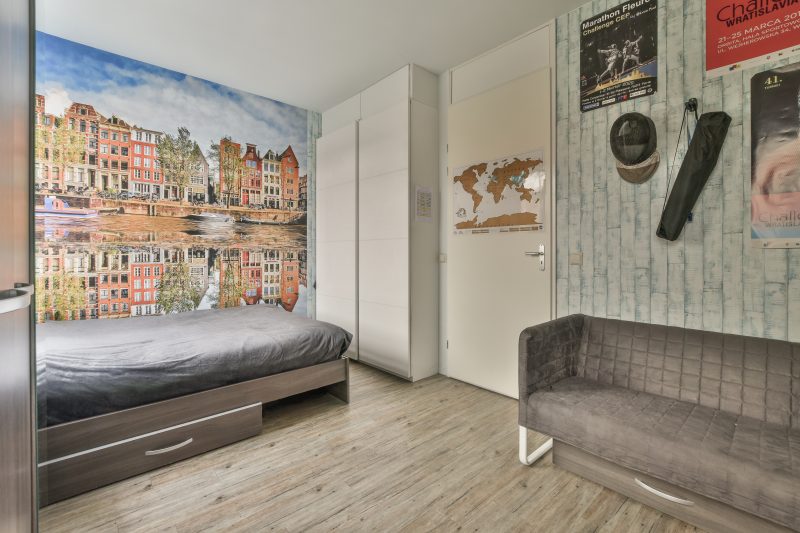 Chambre incluant un lit, un canapé, des cadres, une armoire et un papier peint panoramique paysage