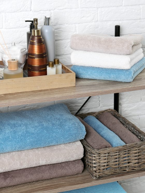 Plateau en bois contenant produits cosmétiques avec des étagères et un panier tressé servant à ranger serviettes salle de bain.
