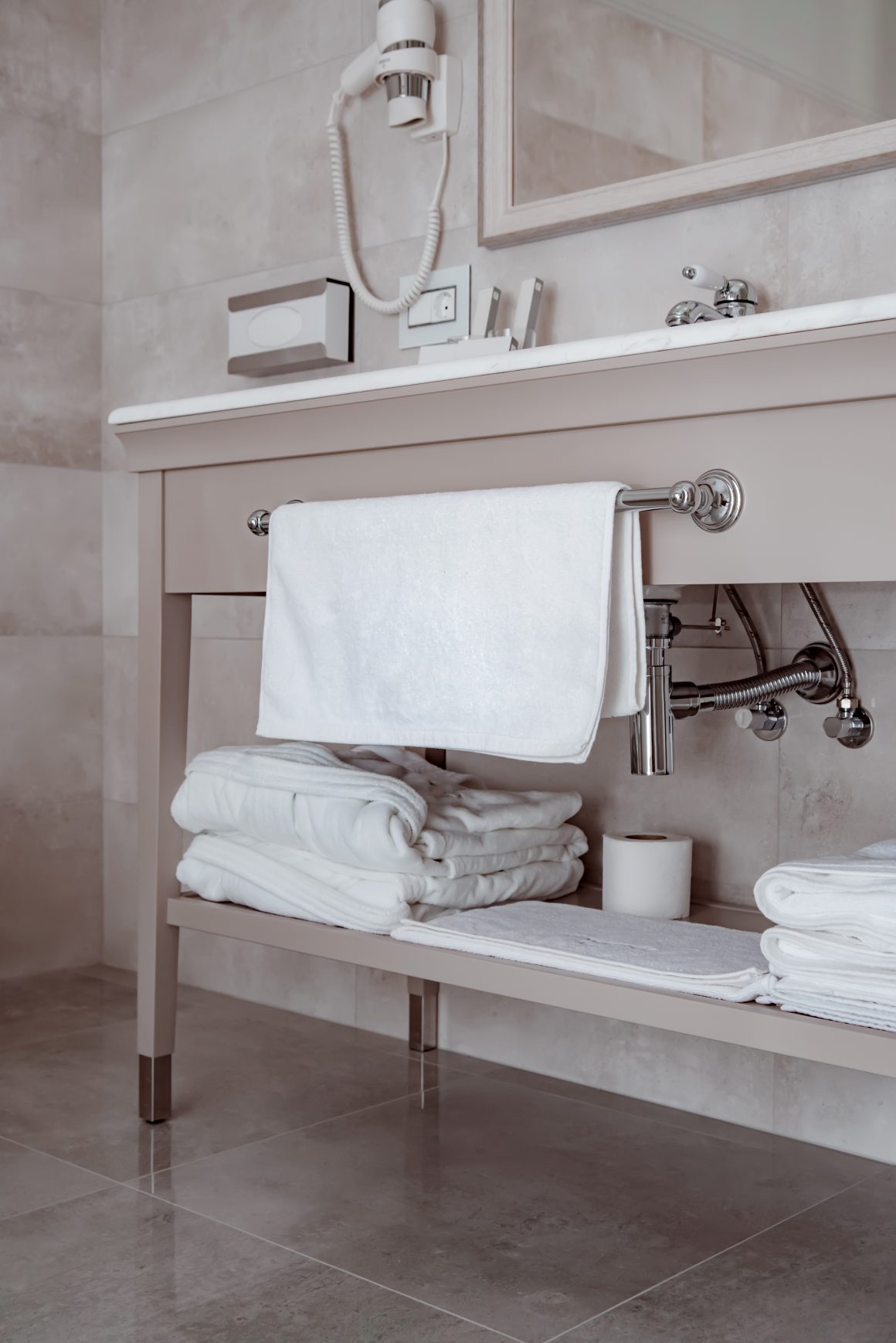 Salle de bain minimaliste incluant miroir, serviettes blanches bien pliées sous le meuble vasque et porte-serviettes.