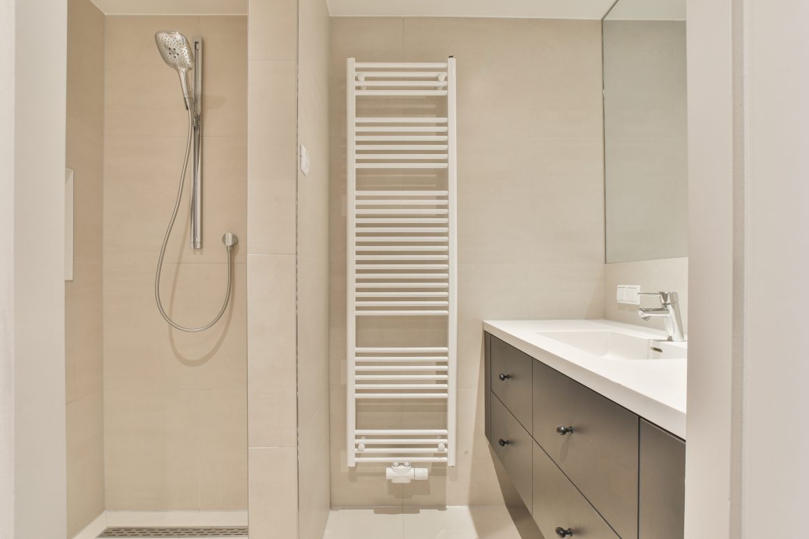 Salle de bain moderne, douche à main, sèche serviettes et lavabo avec meuble noir.