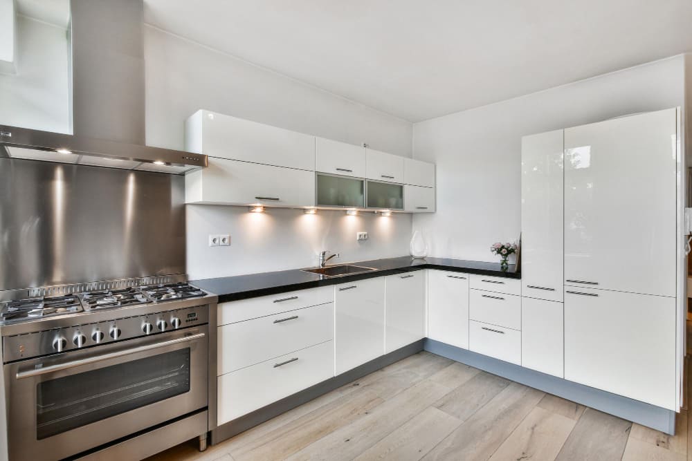 tendance cuisine 2026 en U, avec des façades blanches très épurées, des lumières LED au-dessus du plan de travail