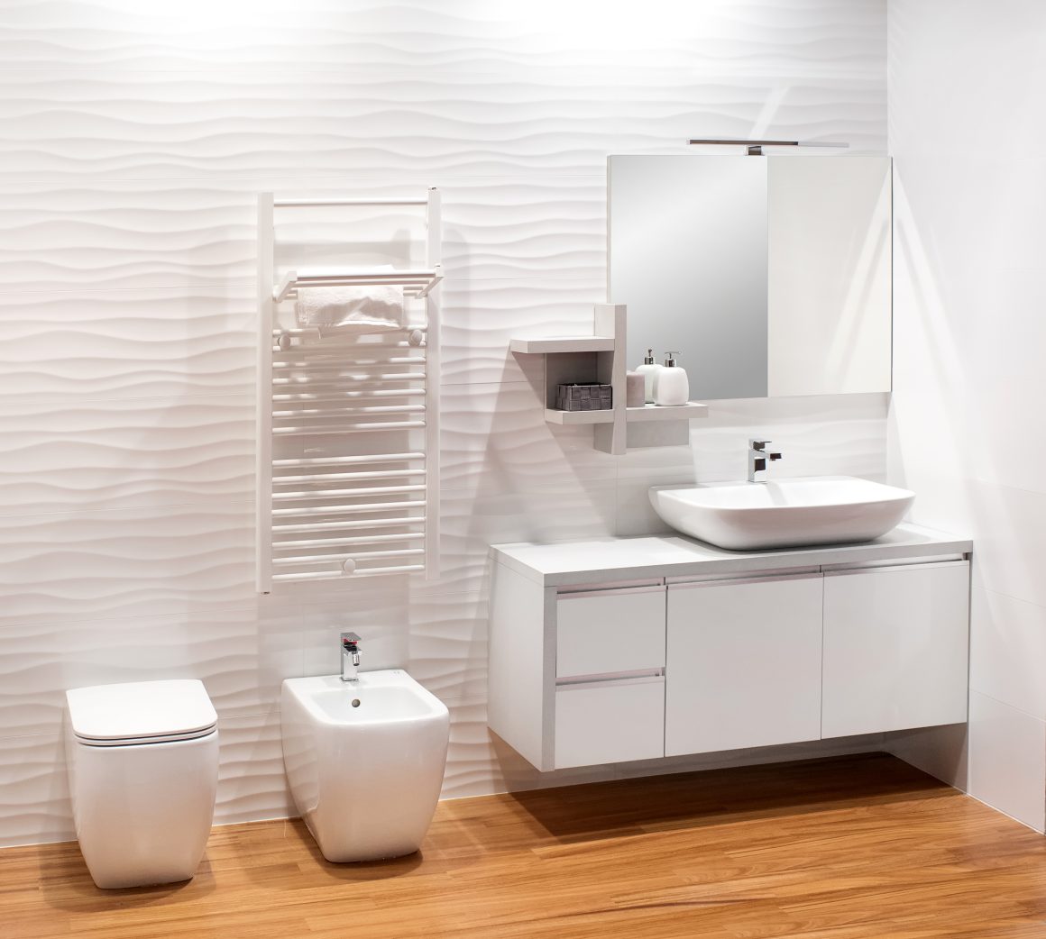 Salle de bain épurée avec lavabo design, miroir, toilettes et porte-serviettes.