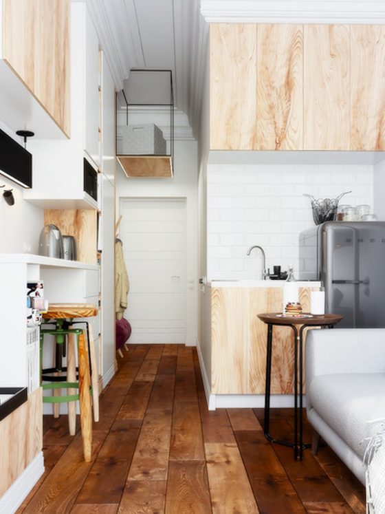 Aménager studio 10m2 avec canapé gris, kitchenette bois, parquet foncé, déco murale, TV avec étagères