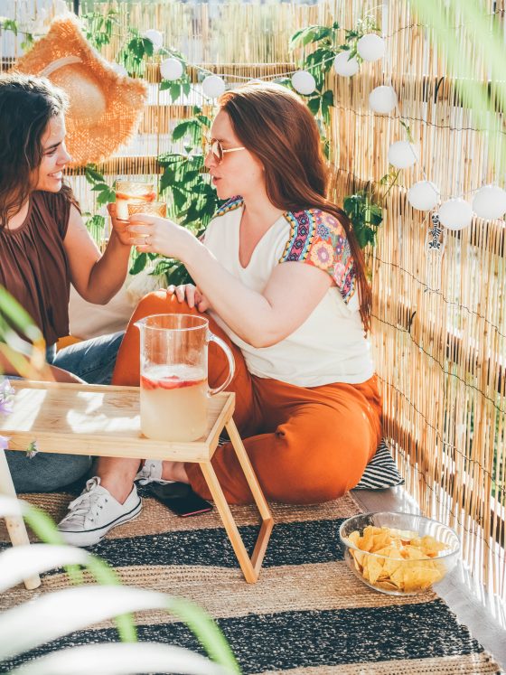 Deux femmes dans une terrasse aménagée avec table basse, guirlandes et plantes