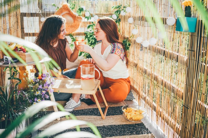 Deux femmes dans une terrasse aménagée avec table basse, guirlandes et plantes