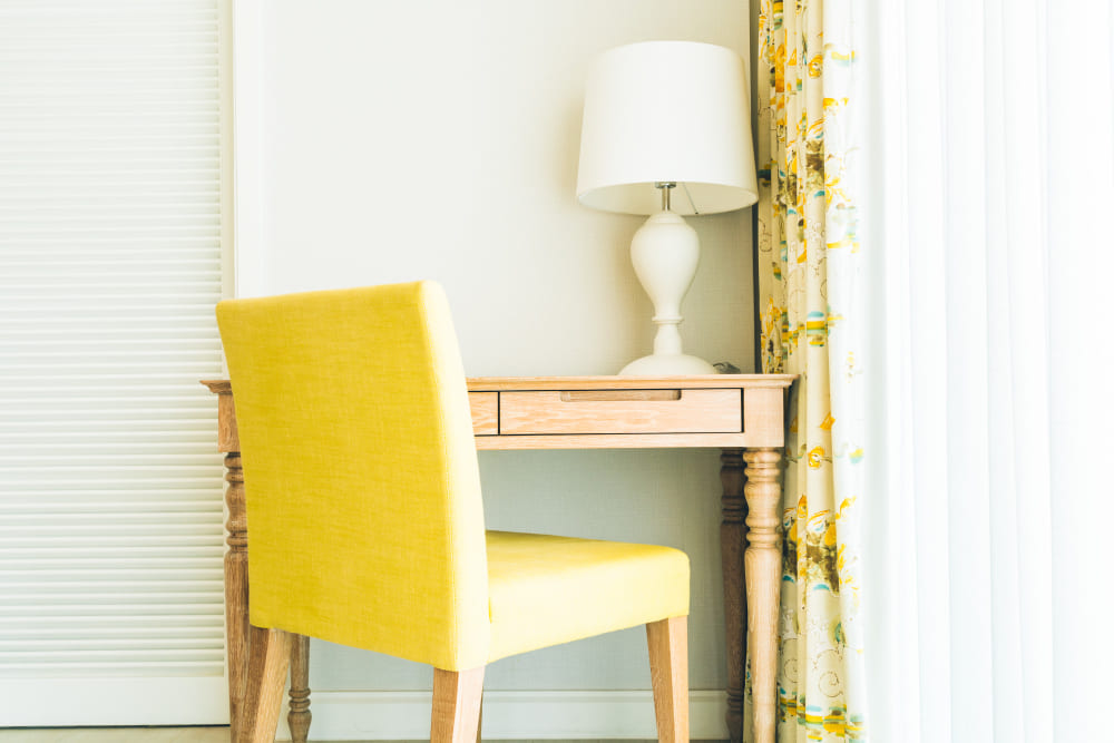 une chaise jaune devant la coiffure en bois et une fenêtre lumineuse