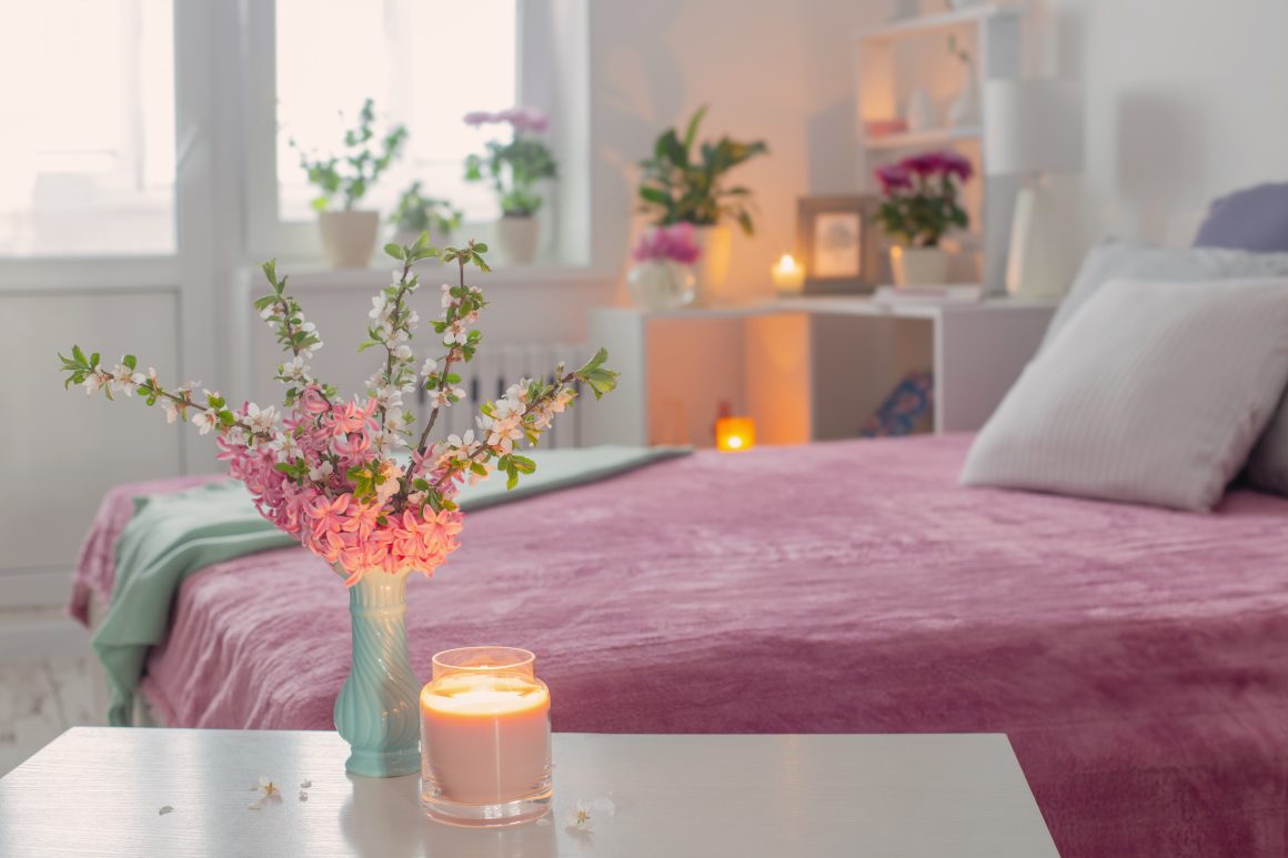Déco chambre relaxante avec des bougies allumées, des fleurs fraîches en vase et une lumière douce