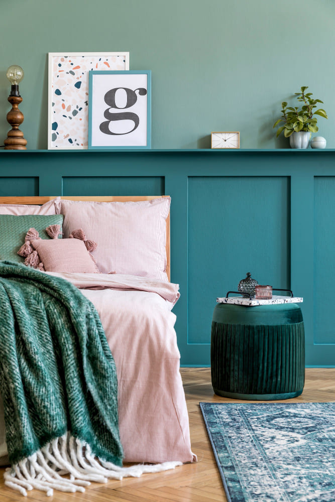 Une chambre avec des soubassements bleu turquoise et un lit dans les tons rose et bleu