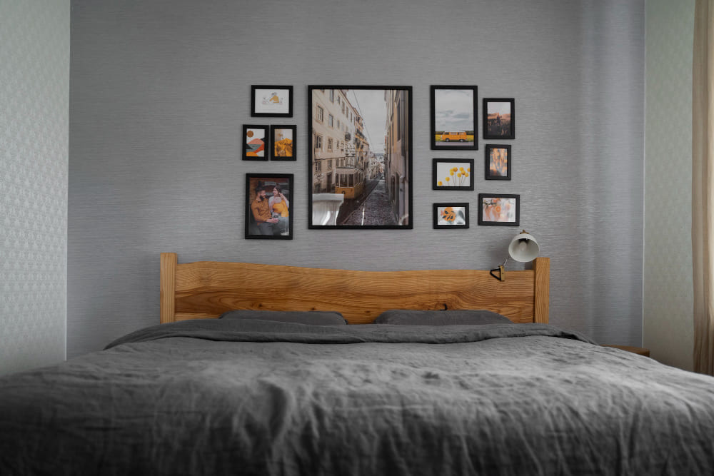 couleur tendance chambre 2026 avec du gris anthracite sur les murs et la parure du lit, et des cadres au mur