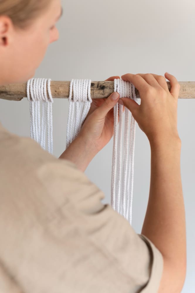 une femme qui confectionne des rideaux DIY avec une branche et une cordelette