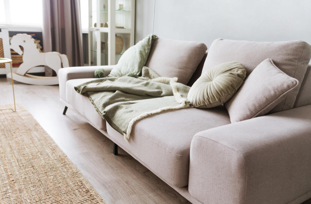 un grand canapé convertible de couleur beige, avec plusieurs coussins dessus