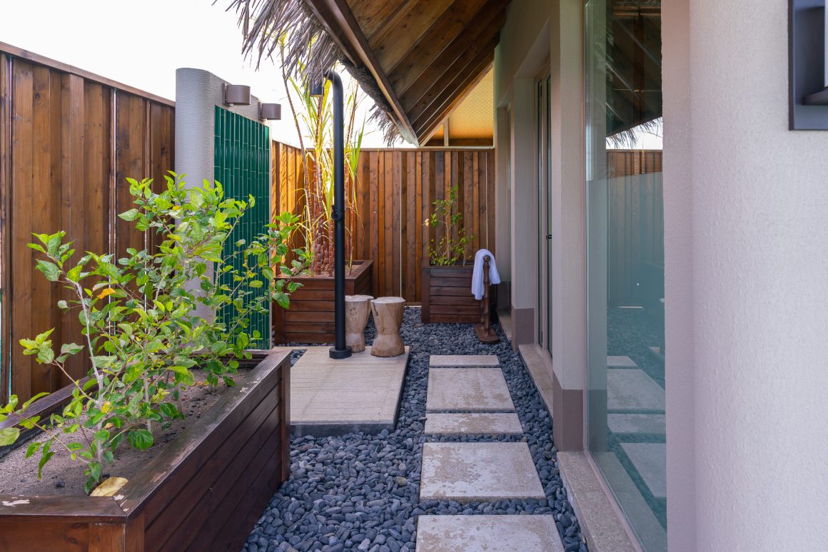 Idée de rénovation d'une façade de maison avec dalles, galets noirs, jardinières en bois, plantes et clôture en bois