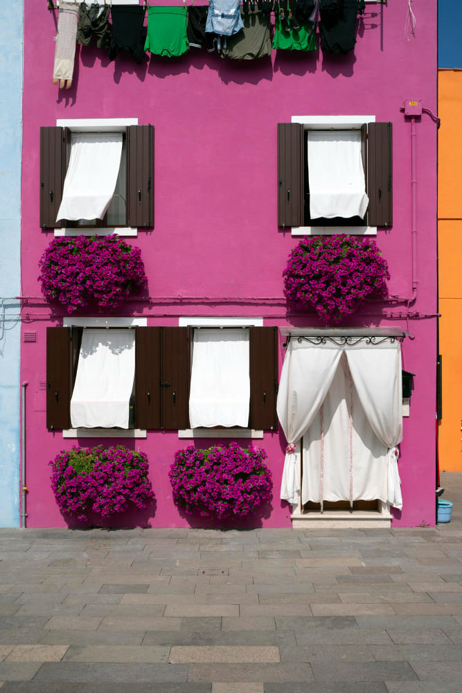 une maison à deux étages avec une façade violette et des stores vénitiens blancs