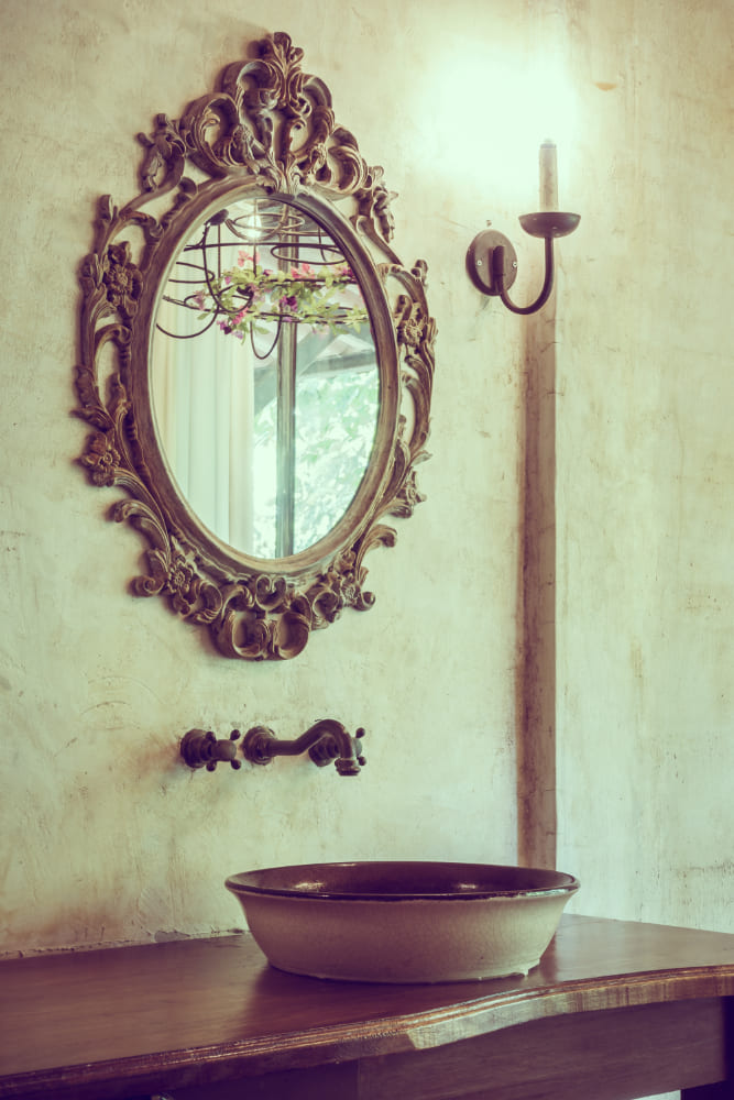 un miroir doré unique et authentique au-dessus d'un lavabo rustique