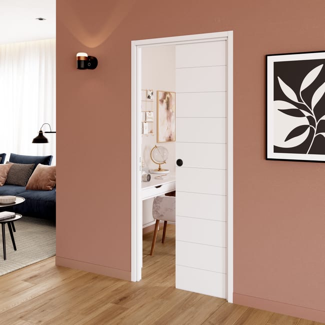 Un intérieur moderne avec mur terracotta et porte coulissante blanche ouverte sur bureau lumineux.