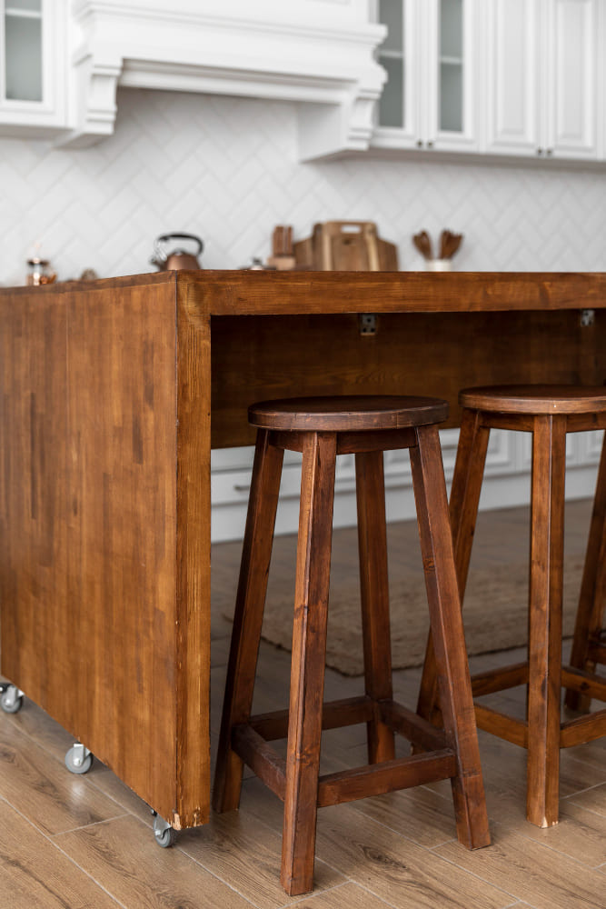 une table en bois exotique sur des roulettes, avec des tabourets de bar devant