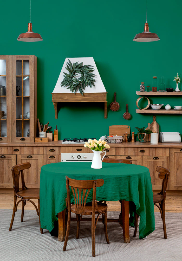 la tendance couleur cuisine 2026 est ici au vert élégant et au bois brut, qui subliment la table et les quatre chaises, ainsi que les lampes suspendues