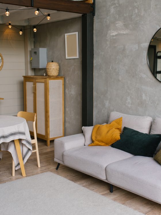 Salon cosy avec canapé clair, coussins colorés, miroir rond, éclairage guirlande : la tendance déco 2026