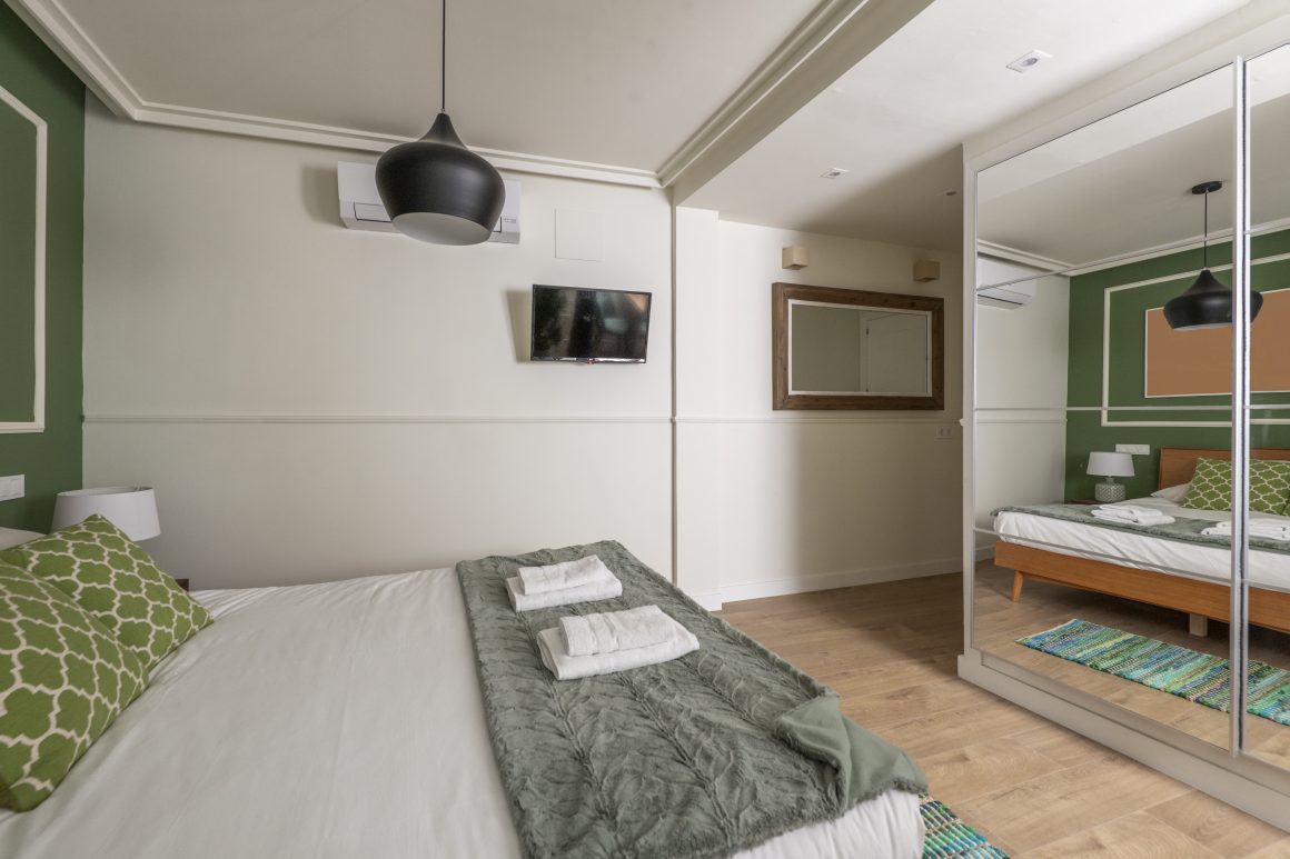 Aménagement chambre 12m2 aux tons verts avec lit, suspension, dressing et grand miroir