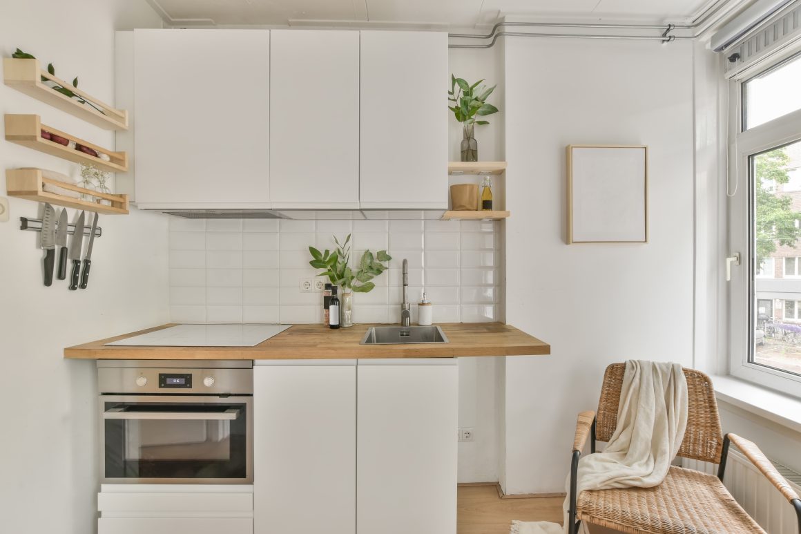 Cuisine compacte au style scandinave et minimaliste avec rangements, étagères ouvertes, plantes et four encastré