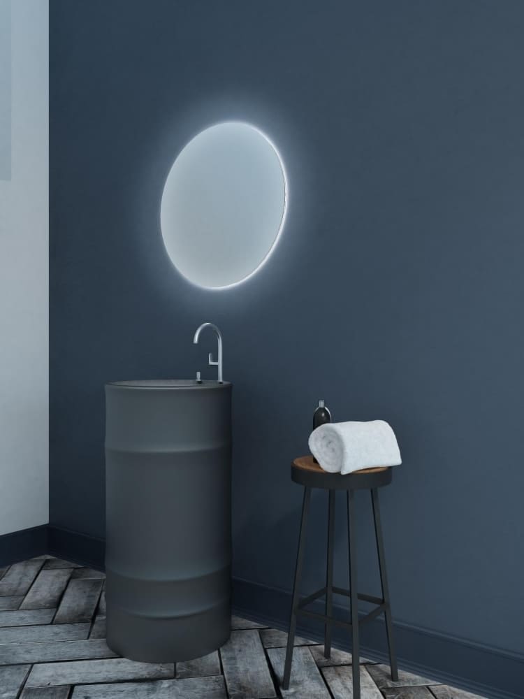 une déco minimaliste avec un mur bleu, du parquet chevrons, un miroir rond et une serviette sur le tabouret