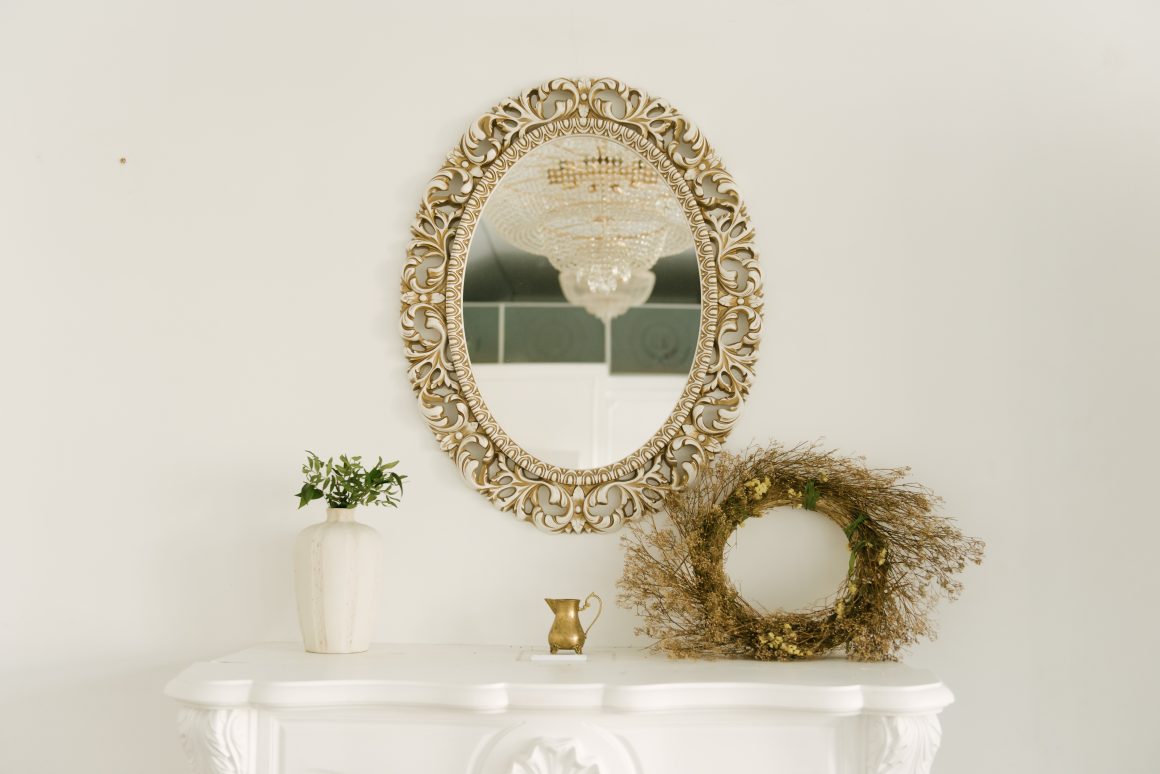 Décoration vintage salon avec miroir ovale doré, vase, couronne de branches et une cheminée blanche