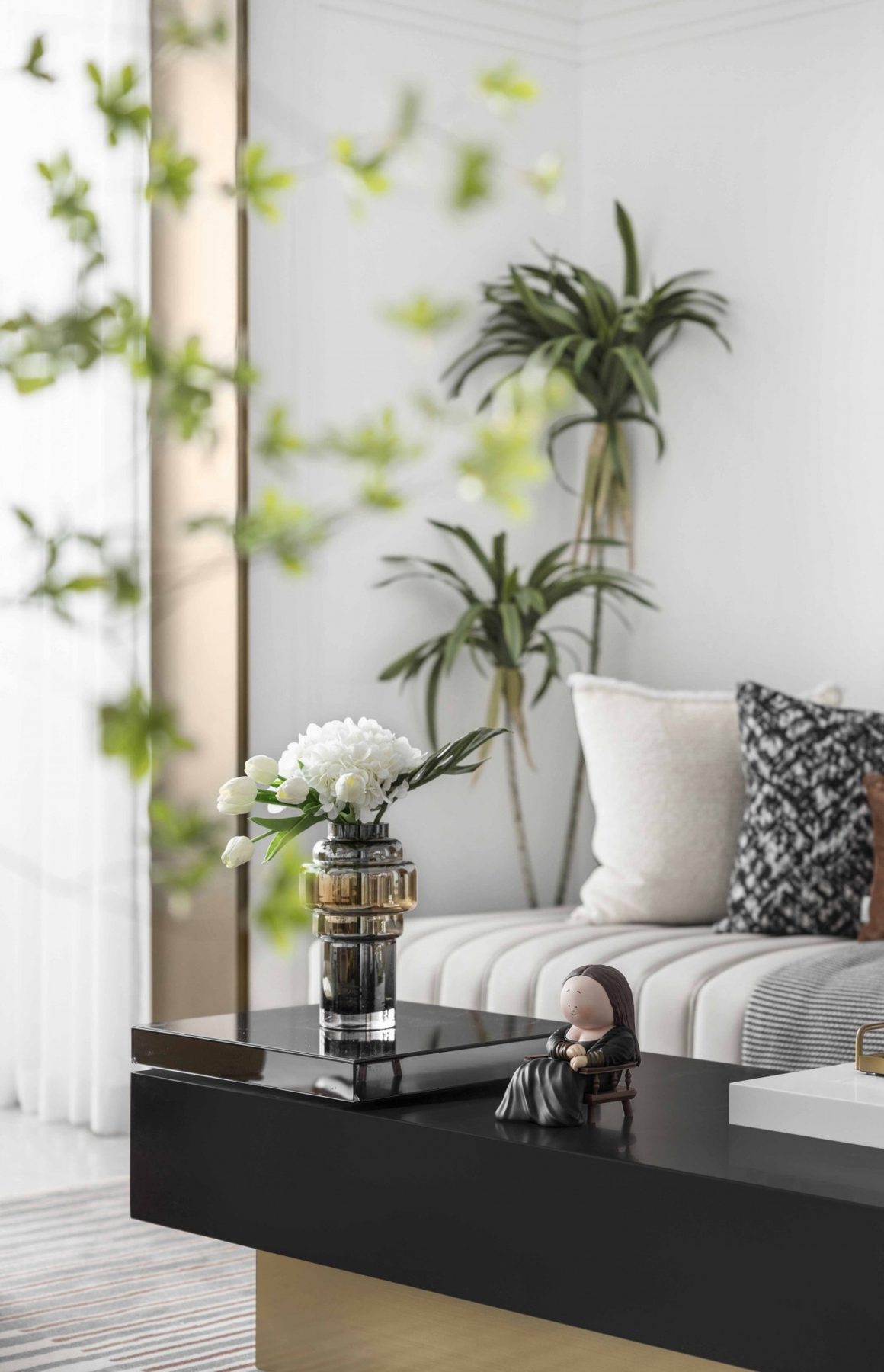 Déco plantes d'intérieur dans un salon lumineux et moderne avec canapé et table noire brillante.